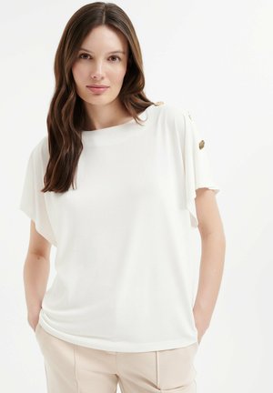Witte top met korte mouwen, een losse pasvorm en een ronde halslijn. Kenmerkt decoratieve gouden accenten op de schouders. Glad stoftextuur.
