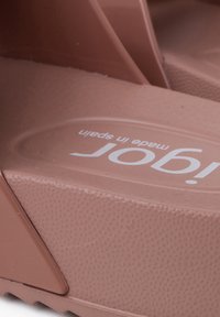 Light brown rubber sandal with textured surface, thick sole, and a prominent white logo reading "igor" angled on the side.