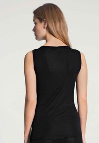 Top nero senza maniche con un design aderente. Tessuto liscio, scollatura arrotondata e bordo grezzo alla base. Stile minimalista.