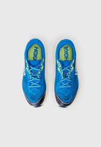 Blue athletic shoes with a textured mesh upper, contrasting neon green accents, flat laces, and a curved white outsole. No visible branding.