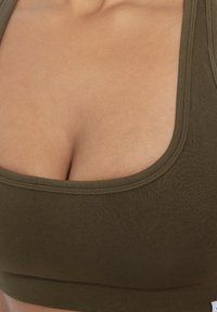 Olivi vihreä ribattu bralette, jossa on syvä kaula-aukko ja tiukka malli, valmistettu pehmeästä, venyvästä kankaasta.