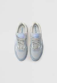 Light blue athletic shoes with a mix of mesh and suede materials, featuring a perforated design, lace-up closure, and textured accents.