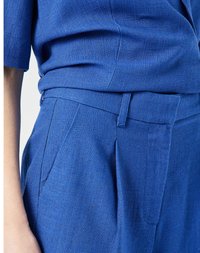 Modrý strukturovaný látkový top s krátkým rukávem, kombinovaný s kalhotami vysokého pasu s záhyby a postranními kapsami.