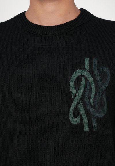 Black knitted sweater with a ribbed collar featuring a green and teal abstract knitted design on the chest.