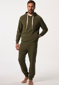Olijfgroene hoodie met beige trekkoorden, gecombineerd met bijpassende jogpants. Beide hebben ribbelboorden en een zachte, gladde textuur.