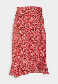 Jupe enveloppante rouge à fleurs avec un ourlet évasé, ornée d'un motif de petites fleurs noires et blanches sur un tissu texturé.
