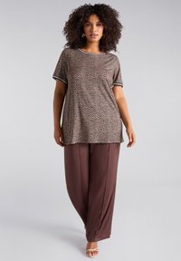 Camiseta de leopardo marrón con manga corta y ribete negro, combinada con pantalones de satén marrones de corte holgado. Diseño sencillo y textura suave.