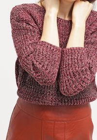 Paksuneulottu neulepaita burgundyssä ja harmaassa, pyöreällä pääntiellä ja kolme neljänneksen hihoilla. Yhdistettynä punaiseen nahkahameeseen.