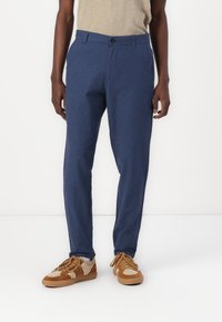 Pantalone u mornarsko plavoj boji od laganog materijala, s ravnim krojem, zatvaranjem na dugme i prednjim džepovima. Uparen s smeškim patikama.