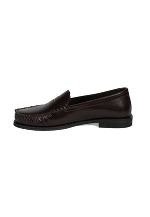 Bruine leren loafers hebben een afgeronde neus, stikdetails rond de rand en een gladde textuur. De zool is plat en zwart.