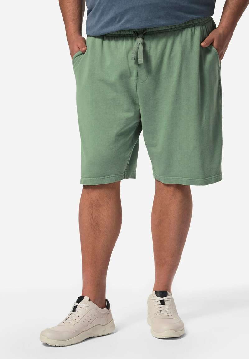 Shorts in cotone verde chiaro con vita elasticizzata e cordino, dotati di tasche laterali e una vestibilità comoda, abbinati a sneakers bianche.