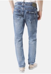 Světle modré denimové džíny s rovnými nohavicemi, které mají dvě zadní kapsy a malou logovou nášivku na pase.