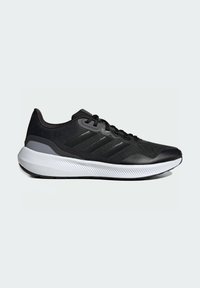 Zapatilla deportiva negra con parte superior texturizada, diseño de tres franjas y una entresuela blanca contrastante con un patrón estriado.
