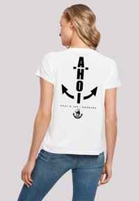 White cotton t-shirt featuring black text "AHOI" and arrows on the back, along with "Knut & Jan | Hamburg" and a sailor icon.