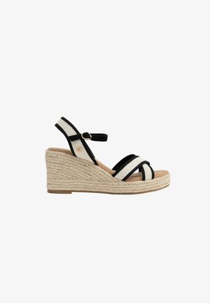 Sandale compensée beige avec des brides en tissu noir et blanc, boucle à la cheville et semelle en corde tressée, vue latérale sur fond blanc.