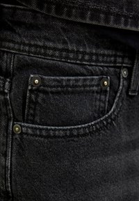 Zwarte denim jeans met een klein voork vakje en zilveren klinknagels. De stof heeft een zachte maar duurzame textuur met subtiele stikseldetails.