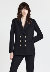 Blazer doppiopetto nero con bottoni dorati, rever a punte e tasche laterali. Design semplice con spalle strutturate e texture liscia.