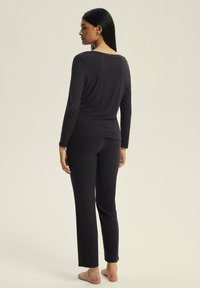 Black ribbed loungewear set featuring long-sleeved top and matching pants, with a relaxed fit and soft texture, showing a simple design.