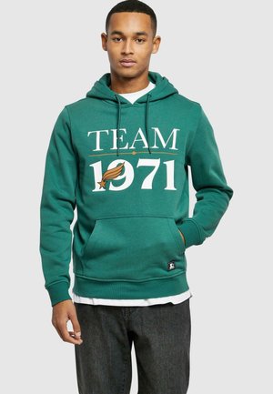 Green hoodie featuring the text "TEAM 1971" in white with a leaf graphic. Made of soft fabric with a front pocket and adjustable hood.