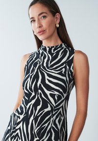 Mustvalge varrukateta kleit, millel on sebratriibuline muster, kõrge kaelus ja tekstuuriga kangas istuva siluetiga.