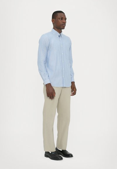 Camisa de manga larga a rayas azul y blanca con cuello abotonado; combinada con pantalones claros y zapatos negros.