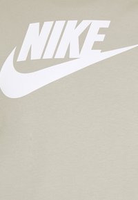 Logotipo blanco de Nike con swoosh sobre fondo de tela beige, centrado y destacado.