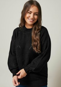 Maglione nero lavorato a maglia con un motivo a rombi e finitura texturizzata. Presenta maniche lunghe, leggermente voluminose, e un colletto a coste.