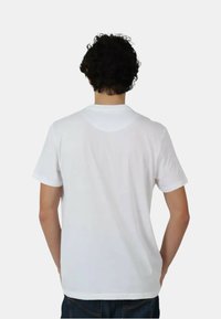 T-shirt bianco in cotone con maniche corte e collo rotondo, caratterizzato da una texture liscia e un design semplice senza pattern o loghi.