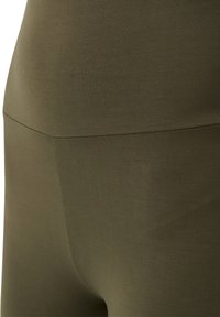 Leggings taille haute vert olive en tissu extensible, avec une texture lisse et un design sans couture au style minimaliste.