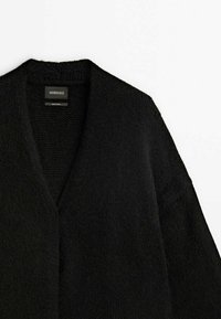 Cardigan en maille noire texturée avec col en V et manches longues, étiqueté Massimo Dutti Édition Limitée, présenté sur fond blanc.