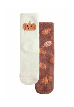 Zwei weiche Socken, eine weiße mit einem lächelnden Kürbis, die andere braun mit verstreuten herbstlichen Blattmustern.