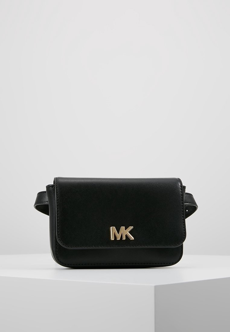 Bolso bandolera de cuero negro con cierre de solapa magnético, que cuenta con un logo "MK" en tono dorado y correa ajustable. Textura suave, diseño compacto.