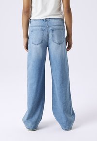 Traperice širokih nogavica u svijetloplavoj boji. Imaju klasični dizajn s pet džepova i visokim strukom, s detaljima šavova i čistim završetkom.