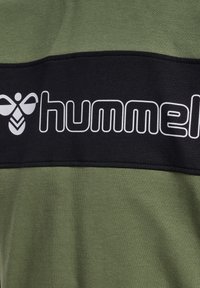 Green fabric with a black horizontal stripe featuring the white "hummel" logo and stylized bee symbol.
