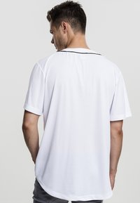 White short-sleeve t-shirt with a rounded hem and black accent at the neckline, featuring a smooth texture and relaxed fit.