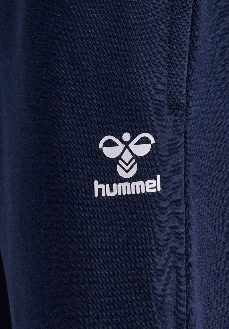 Marineblaue Jogginghose mit einem weißen "hummel"-Logo und einem Bienen-Design, aus weichem Stoff mit einer strukturierten Oberfläche.