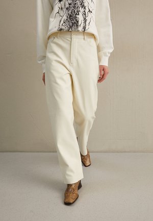 Λευκά, tailored παντελόνια με ίσια εφαρμογή, σε συνδυασμό με ένα γραφικό πουλόβερ και καφέ, υφασμάτινα μποτάκια μέχρι τον αστράγαλο. Λεπτό ύφασμα και καθαρές γραμμές.