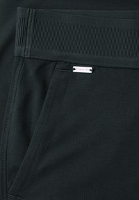 Tmavé látkové kalhoty s žebrovaným pasem a přední kapsou s malou obdélníkovou stříbrnou cedulkou s logem "Street One".