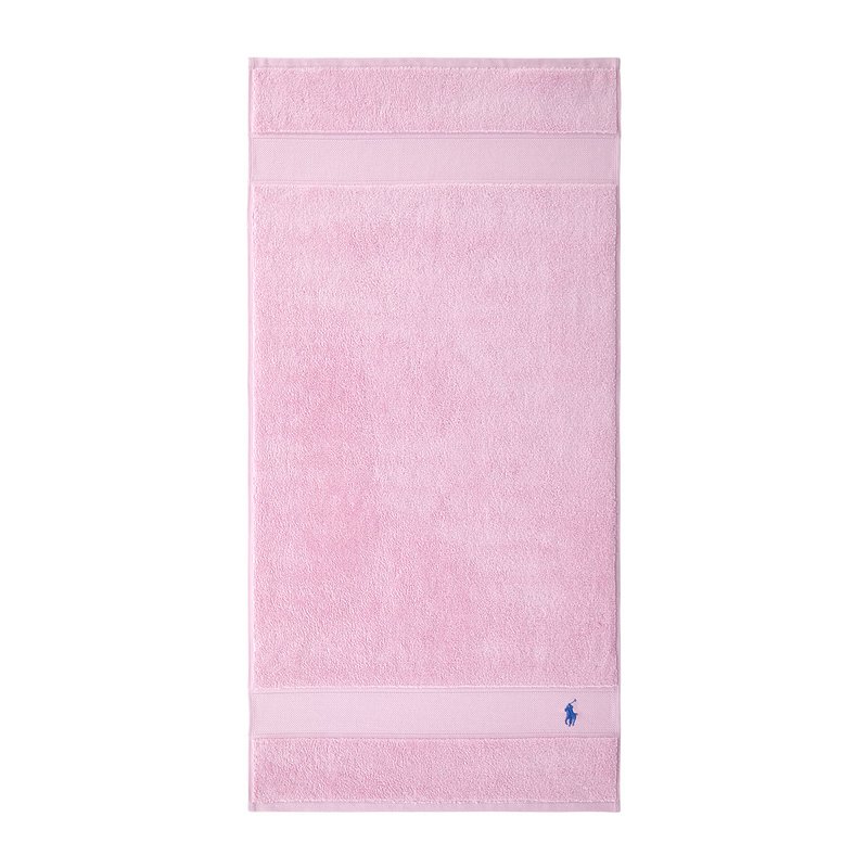 Ροζ πετσέτα μπάνιου από ύφασμα τερι με μαλακή υφ ή, διακοσμημένη με δύο οριζόντιες ρίγες και ένα μπλε λογότυπο κεντημένο στην κάτω γωνία.
