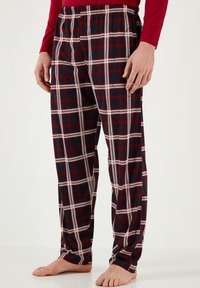 Rutet pyjamabukser i navy, rød og hvid med elastisk talje. Lavet af blødt stof, med brede ben og en afslappet pasform.