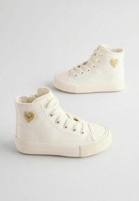 Kõrge säärega tossud beežvalgest lõuendist, tekstuurse viimistlusega, millel on kuldne südamekujulise plaastri külgedel ja kummist varbakaas.