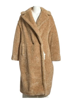 Long manteau teddy marron clair duveteux avec larges revers et poches latérales présenté sur un buste de mannequin blanc.