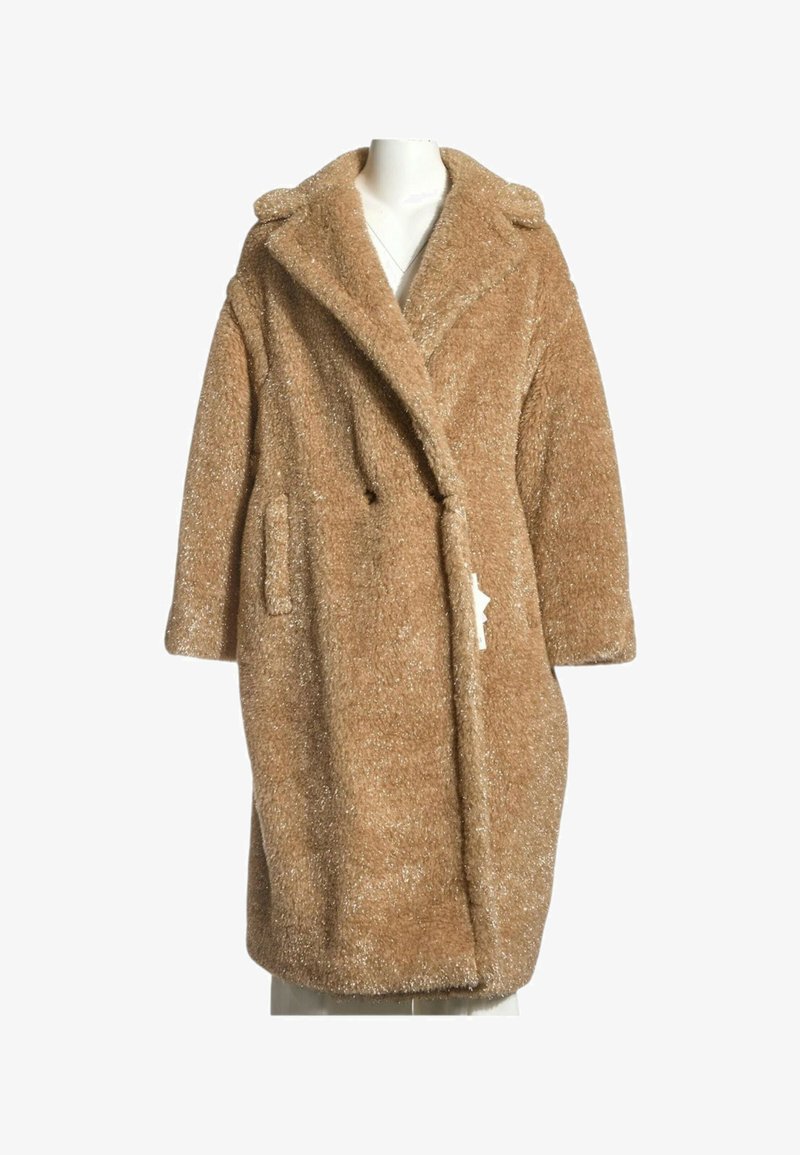 Long manteau teddy marron clair duveteux avec larges revers et poches latérales présenté sur un buste de mannequin blanc.