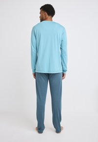 Hellblaues Langarmhemd und türkisfarbene Hose mit weißen Polka-Dots, aus weichem Stoff, mit bequemer Passform und Rundhalsausschnitt.