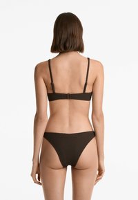 Bikini v rjavi barvi z teksturo, ki ima nastavljive naramnice, z zaponko na hrbtni strani in minimalističnim dizajnom za spodnji del.