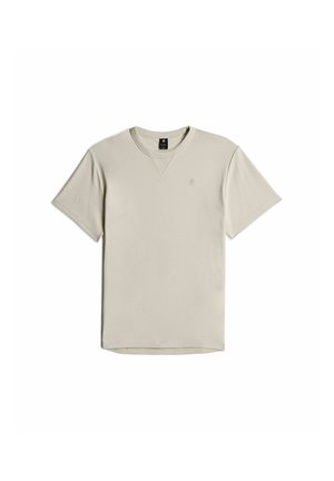 Lichtbeige kortekoo shirt gemaakt van zachte stof, met een ronde halslijn en een klein logo op de borst. Eenvoudig ontwerp, relaxte pasvorm.