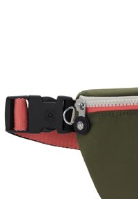 Pochette en tissu vert olive avec une sangle rose, dotée d'une fermeture éclair blanche, d'une boucle noire et d'un petit logo rond.