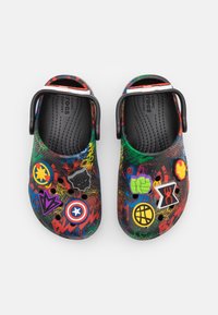 Multicolored clogs with a graffiti pattern, featuring character-themed 3D embellishments and a rear strap for secure fit.