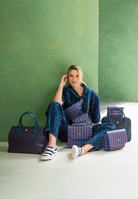 Sammlung von fünf Taschen in verschiedenen Formen und Größen. Die Materialien umfassen Stoff und Leder, mit blauen und burgunderfarbenen Farbtönen sowie gestreiften Mustern.