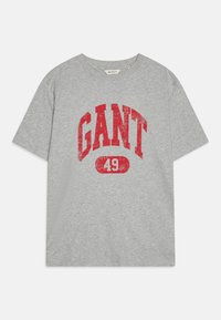 Pelēks kokvilnas T-krekls ar nolietotu sarkanu apdruku, kurā redzams vārds "GANT" un skaitlis "49" bold fontā. Klasiska apkakle un īsām piedurknēm. Mīksta tekstūra.